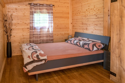 Slaapkamer in het mobilhome Robinzonski Kamp Hofman in Kroatië met houten wanden en tweepersoonsbed.