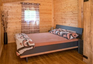 Slaapkamer in het mobilhome Robinzonski Kamp Hofman in Kroatië met houten wanden en tweepersoonsbed.
