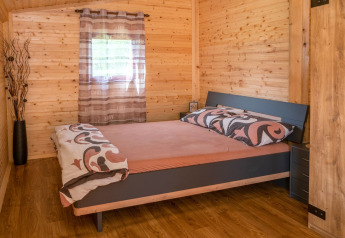 Camera da letto nella casa mobile Robinzonski Kamp Hofman in Croazia con pareti rivestite in legno.
