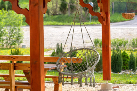 Buitenruimte met hangstoel en houten banken bij Robinzonski Kamp Hofman, privé bungalow in Kroatië