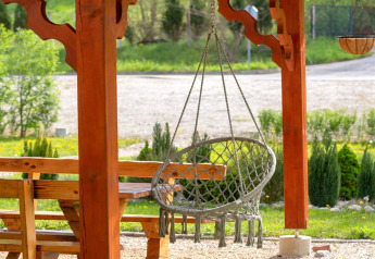 Outdoor area with a hanging chair and wooden benches at Robinzonski Kamp Hofman, private bungalow Croatia