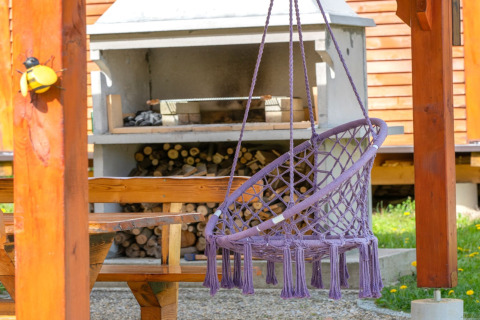 Paarse hangstoel en houten picknicktafel bij open haard in Robinzonski Kamp Hofman in Kroatië.