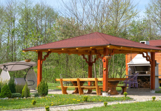 Overdekte houten prieel met bankjes, schommel, barbecue en tuin in Robinzonski Kamp Hofman, Kroatië.