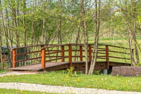 Houten brug bij het Robinzonski Kamp Hofman mobilhome, omringd door bomen en groen in Kroatië.
