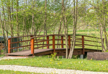 Ponte di legno vicino alla casa mobile Robinzonski Kamp Hofman circondato da alberi in Croazia.