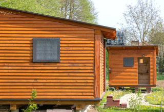 Twee houten bungalow-mobiele huizen bij Robinzonski Kamp Hofman, Kroatië, te midden van groene natuur.