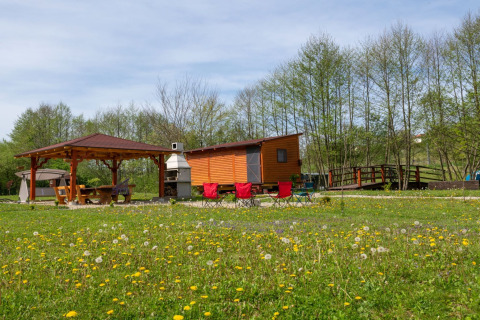 Stacaravan bij Robinzonski Kamp Hofman met overkapt terras, bloemenweide en bomen op de achtergrond.