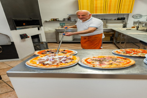 Un pizzero prepara pizzas frescas en la cocina del mobil home Cottage «Cesenatico» en Italia.