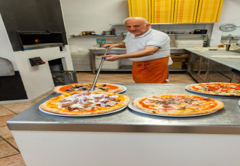 En pizzabager i et mobilhome Cottage «Cesenatico» i Italien forbereder frisklavede pizzaer i køkkenet.