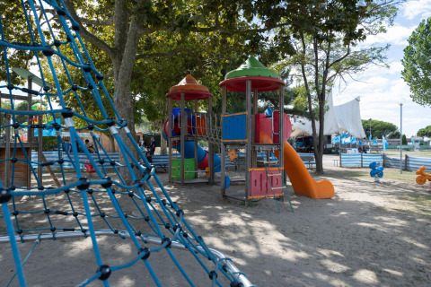 Parque infantil con red para escalar y estructuras de colores bajo árboles en Cottage 'Cesenatico', Italia.