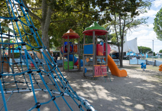 Spielplatz mit Kletternetz und bunten Spielgeräten unter Bäumen im Cottage 'Cesenatico' in Italien.