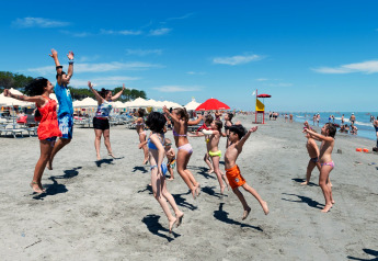 Kinderen en volwassenen springen en spelen op het strand bij mobilhome Cottage ‘Cesenatico’ in Italië.