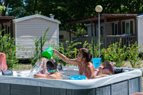 Familia disfruta de un jacuzzi frente a la casa móvil Cottage «Cesenatico» en Italia, niños jugando.