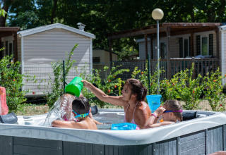 Familia disfruta de un jacuzzi frente a la casa móvil Cottage «Cesenatico» en Italia, niños jugando.