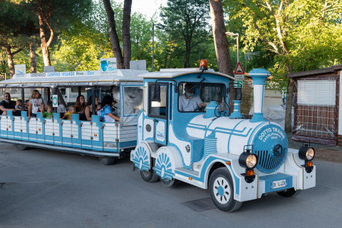 Ein kleiner Touristenzug voller fröhlicher Passagiere fährt durch das Mobilheimgebiet Cottage Cesenatico in Italien.