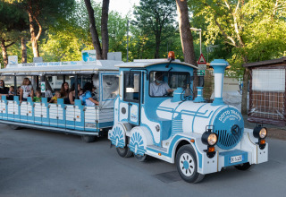 Ein kleiner Touristenzug voller fröhlicher Passagiere fährt durch das Mobilheimgebiet Cottage Cesenatico in Italien.