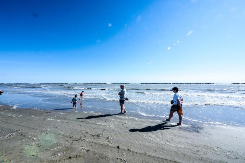 Menschen spazieren und spielen am Strand am Meer bei sonnigem Wetter in der Nähe von Cottage Cesenatico, Italien