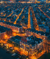Vista aérea nocturna de una ciudad con canales y alojamientos glamping en un parque vacacional iluminado.