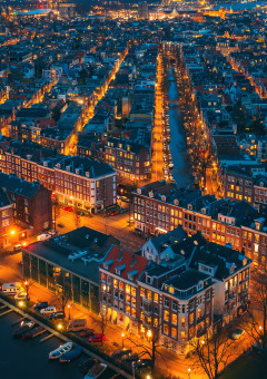 Vista aérea nocturna de una ciudad con canales y alojamientos glamping en un parque vacacional iluminado.