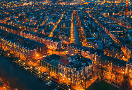 Vista aérea nocturna de una ciudad con canales y alojamientos glamping en un parque vacacional iluminado.