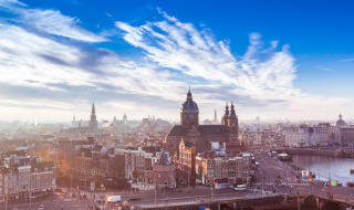 Vista sul centro di Amsterdam con edifici storici, canali e cielo blu in una luminosa giornata di sole.