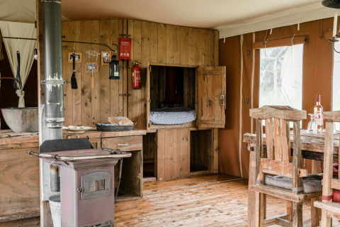 Interno rustico di una lodge con mobili in legno e stufa presso Duynlodge - Duynpark, Paesi Bassi.