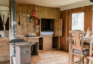 Interno rustico di una lodge con mobili in legno e stufa presso Duynlodge - Duynpark, Paesi Bassi.