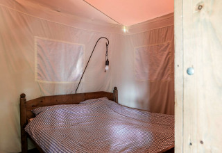 Slaapkamer in Duynlodge - Duynpark, Nederland, met houten bed en geruit beddengoed.