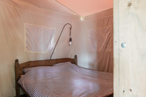 Camera da letto in Duynlodge - Duynpark nei Paesi Bassi con letto in legno e biancheria a quadri.