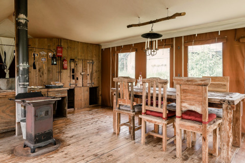 Rustieke eetkamer met houten meubels en kachel bij Duynlodge - Duynpark in Nederland.