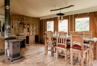 Rustieke eetkamer met houten meubels en kachel bij Duynlodge - Duynpark in Nederland.