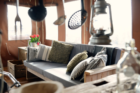 Gezellige lodge met houten zitbank, kussens, lantaarn en bloemen, Duynlodge in Nederland.