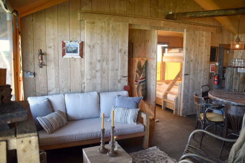 Interior of Kidz Lodge in the Netherlands featuring a sofa, dining table, and wooden bunk beds.