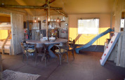Interno di Kidz Lodge nei Paesi Bassi con tavolo da pranzo, letti a castello, scivolo e parete da arrampicata.