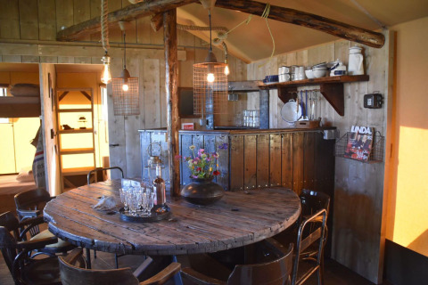 Zona pranzo rustica nella Kidz Lodge, Paesi Bassi, con tavolo rotondo in legno e scaffali di cucina.