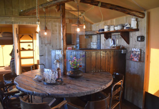 Zona pranzo rustica nella Kidz Lodge, Paesi Bassi, con tavolo rotondo in legno e scaffali di cucina.