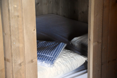 View of a bed with white pillows and a blue checked blanket at Kidz Lodge in the Netherlands.
