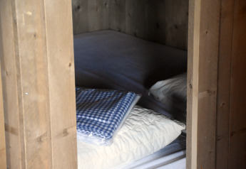 Vista di un letto con cuscini bianchi e coperta a quadri blu al Kidz Lodge nei Paesi Bassi.