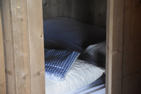 Vista di un letto con cuscini bianchi e coperta a quadri blu al Kidz Lodge nei Paesi Bassi.