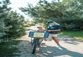 Donna e bambino si godono una giornata di sole con una bicicletta su un sentiero di un lodge tra alberi.