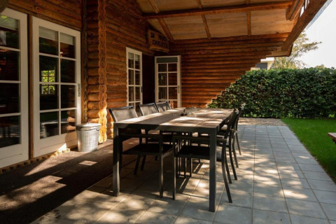 Udendørs spiseplads ved træhytte, Paalchalet 723, Belgien, med bord, stole og grøn hæk.
