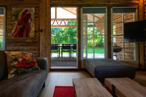 Hyggelig stue i Paalchalet 723, Belgien, med store vinduer, træinteriør og udsigt til grøn have.