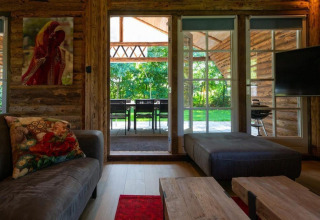 Hyggelig stue i Paalchalet 723, Belgien, med store vinduer, træinteriør og udsigt til grøn have.