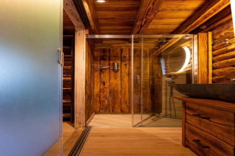 Badeværelse med trævægge og loft, glasbruser og rund spejl i Paalchalet 723, Belgien.