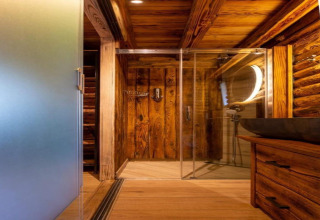 Badeværelse med trævægge og loft, glasbruser og rund spejl i Paalchalet 723, Belgien.