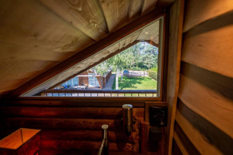 Udsigt fra et trekantet vindue i træindretning på Paalchalet 723-lodgen, med have og træer udenfor.