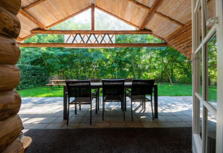 Udsigt fra indgangen til en hytte ved Paalchalet 723 i Belgien med terrassebord og stole i det grønne.