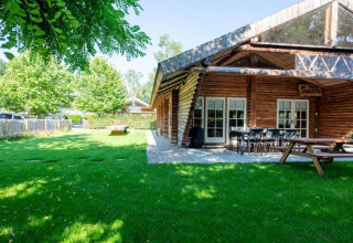 Trælodge med terrasse og grøn have ved Paalchalet 723 i Belgien, ideel til udendørs ophold.