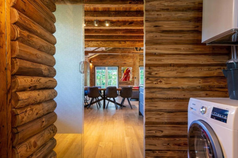 Interiør af bjælkehytte med trævægge, vaskemaskine og udsigt til spisebord, Paalchalet 723, Belgien.