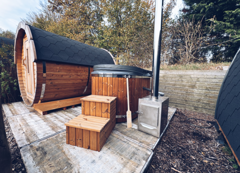 Outdoor glamping pod featuring a wooden sauna and hot tub at REBL Outdoor in the Netherlands, nature setting.